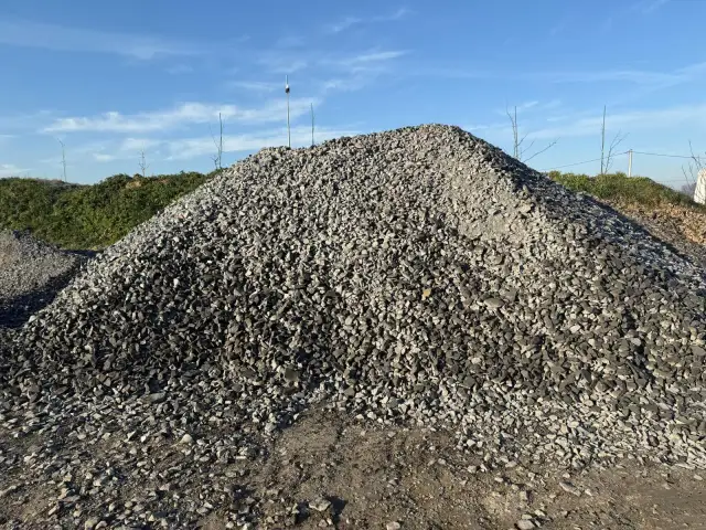 Duża hałda kruszywa budowlanego na tle błękitnego nieba.