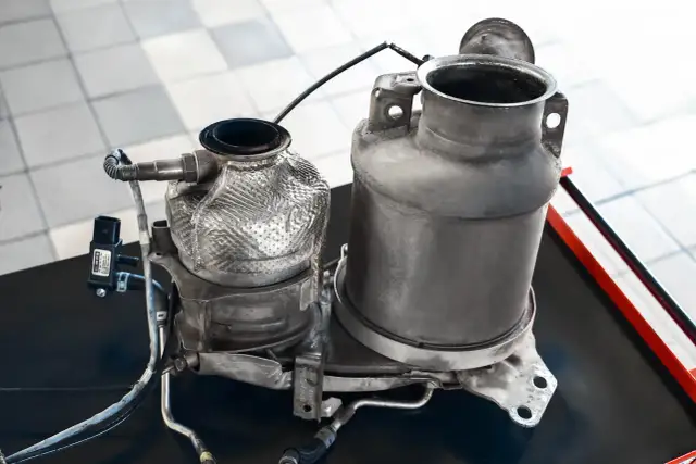 Dwa elementy układu wydechowego Audi, jeden z osłoną termiczną, gotowe do czyszczenia. Zastanawiasz się, ile gram sadzy w DPF Audi?