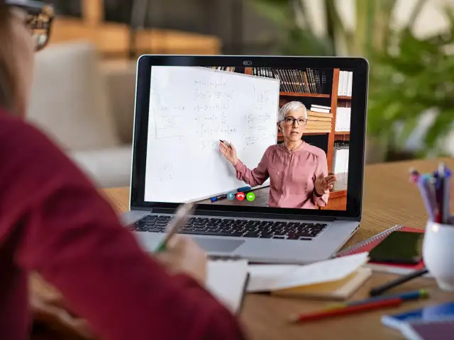 Nauczycielka tłumaczy matematykę na lekcji zdalnej na ekranie laptopa.