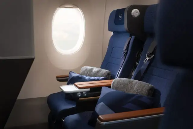 Lufthansa Premium Economy Sitze mit Kissen und Decken neben einem Fenster.