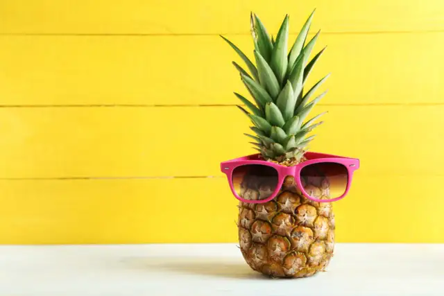 Ananas w okularach przeciwsłonecznych na żółtym tle. Poznaj jego niezwykłe ananas właściwości!