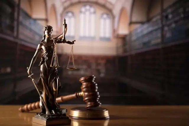 Temida z wagą i mieczem, obok młotka sędziowskiego. Symbol sprawiedliwości, rozstrzygania sporów, w tym służebności mieszkania.