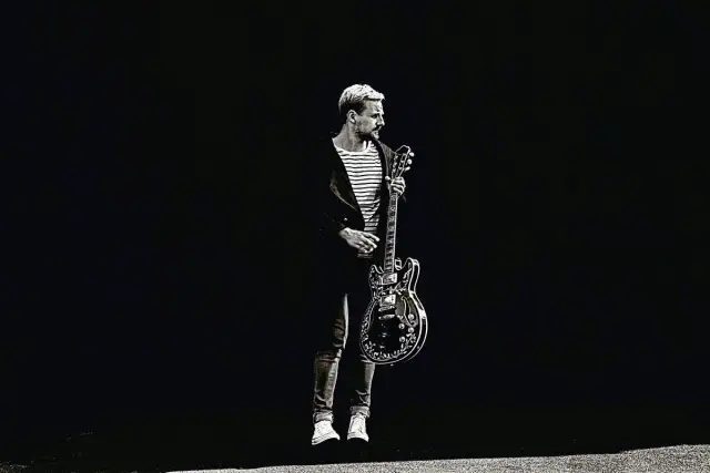 Paweł Domagała z gitarą, jakby gotowy do wykonania utworu "Weź nie pytaj".