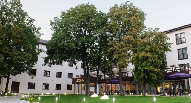 Nowoczesny budynek Teodorka Med & Spa otoczony zielenią i oświetlony lampkami.