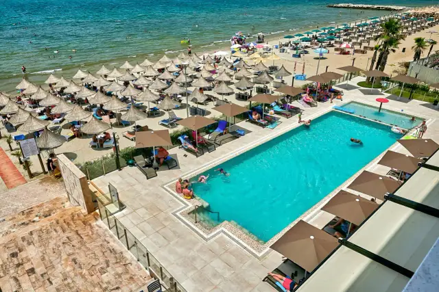 Widok z lotu ptaka na hotelowy basen i plażę z leżakami i parasolami w Durrës, Albania.