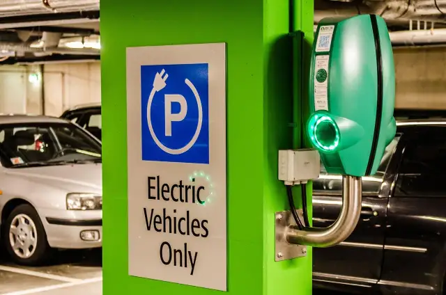 Znak "Tylko pojazdy elektryczne" i zielona ładowarka EVbox. Zastanawiasz się, ile kosztuje ładowanie samochodu elektrycznego w domu?