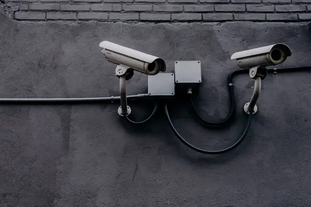 Dwie kamery monitoringu na szarej ścianie. Czy to tylko bezpieczeństwo, czy może coś więcej?