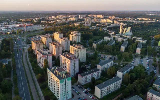 Widok z lotu ptaka na osiedle bloków mieszkalnych i drogę z samochodami o zachodzie słońca.