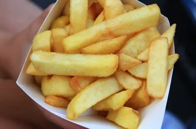 Złociste, grube frytki belgijskie w papierowym rożku.