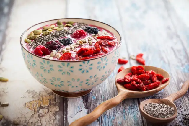 Miseczka smoothie z owocami i nasionami. Nasiona chia, jagody, maliny, pestki dyni i słonecznika. Niski indeks glikemiczny.