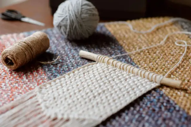 Dwukolorowy szalik na drutach w trakcie robienia, z kłębkami włóczki i nożyczkami.