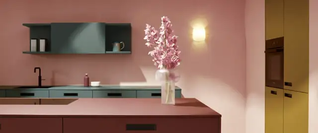Elegante cocina rosa con encimeras de color burdeos, armarios verde azulado y un ramo de flores rosas.