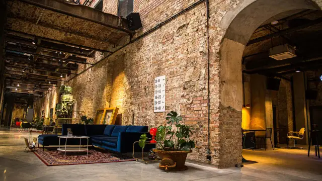 Wnętrze hotelu Cukrownia Żnin: industrialny klimat, ceglane ściany, wygodna granatowa sofa i zabytkowa maszyna.