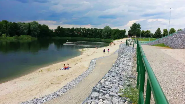 Żwirownia międzyrzec podlaski: piaszczysta plaża, kąpielisko z pomostami, ludzie odpoczywający nad wodą, zielone drzewa w tle.