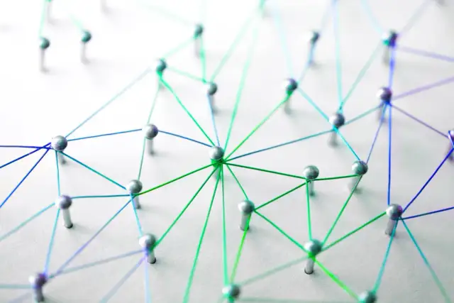 Netzwerk aus silbernen Pins und bunten Fäden auf weißem Untergrund.