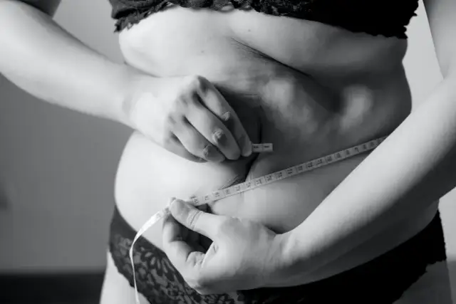 Kobieta mierzy talię centymetrem, szukając sposobu, jak schudnąć 5 kg w 3 dni.