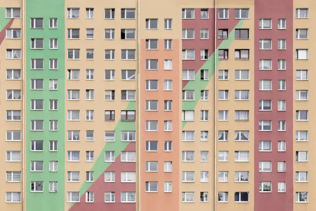 Kolorowy blok mieszkalny z wieloma oknami. Szukasz sposobu, jak przyspieszyć dostanie mieszkania komunalnego?
