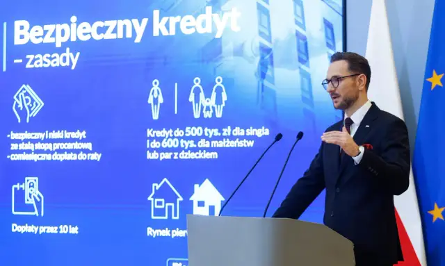 Mężczyzna w garniturze prezentuje zasady "Bezpiecznego kredytu" z dopłatą do rat. Program oferuje kredyt 2 procent dla singli i małżeństw.