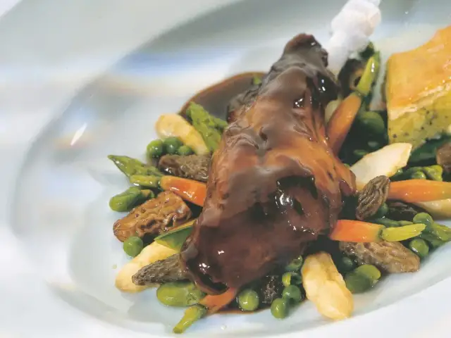 Ein köstliches Kaninchen-Rezept: zartes Kaninchenfleisch in dunkler Sauce, serviert mit Spargel, Erbsen, Karotten und Morcheln.