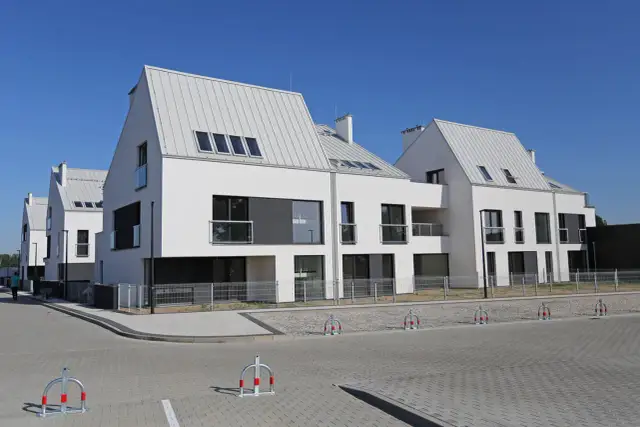 Nowoczesne domy szeregowe z białymi elewacjami i szarymi dachami tworzą malowniczą panoramę osiedla.