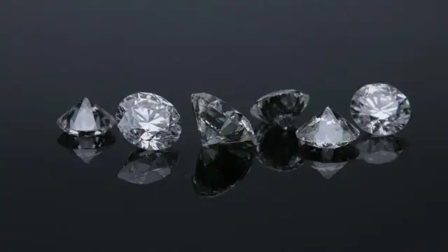Siedem błyszczących diamentów na czarnym tle. Co oznacza diament na sympatii? Symbol trwałości i piękna, jak te kamienie.