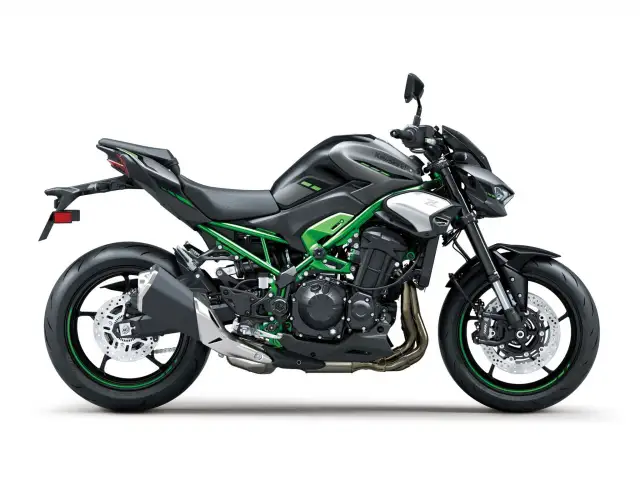 Czarny motocykl Kawasaki Z900 z zielonym stelażem i akcentami. Potężna maszyna gotowa na przygodę.