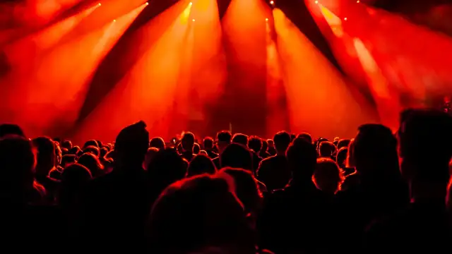Tłum ludzi na koncercie w Polsce, rozświetlony czerwonymi światłami sceny.