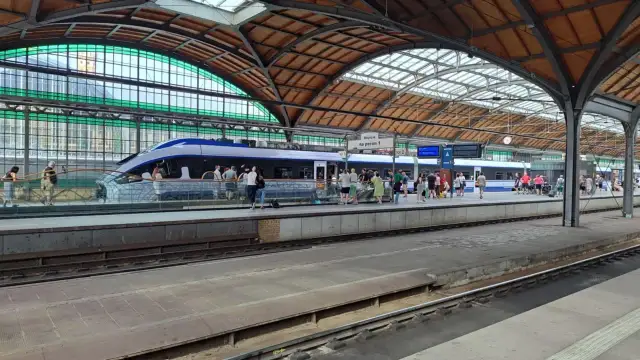 Nowoczesny pociąg kraków wrocław na peronie, pasażerowie czekają na podróż pod zabytkowym zadaszeniem dworca.