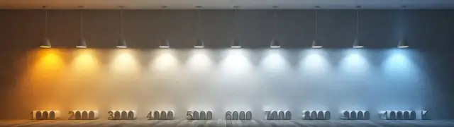 Rząd lamp oświetla ścianę, ukazując pełne spektrum barwy światła od ciepłej żółci do zimnego błękitu, z oznaczeniami temperatur barwowych.