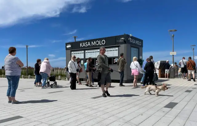 Ludzie stojący w kolejce do kasy biletowej "Kasa Molo" w Kołobrzegu.