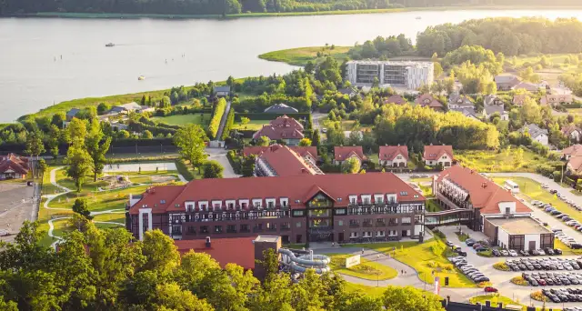 Widok z lotu ptaka na kompleks hotelowy Radisson z czerwonymi dachami, otoczony zielenią i jeziorem.