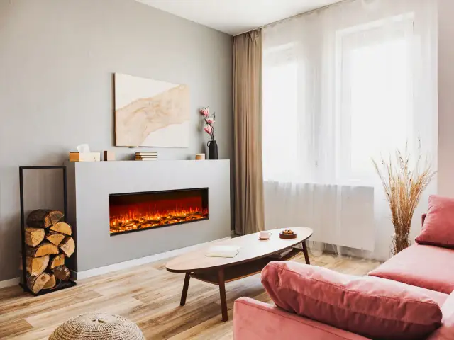 Nowoczesny salon z dużym kominkiem elektrycznym, który tworzy przytulną atmosferę. Obok stos drewna.