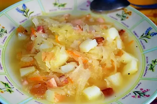 Gęsty, sycący kapuśniak z ziemniakami i kawałkami wędzonki, podany w ozdobnej misce.