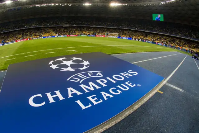 Logo Ligi Mistrzów UEFA na tle stadionu piłkarskiego.