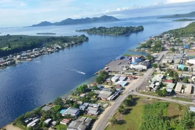 Widok na zatokę z miasteczkiem na wybrzeżu, portem i łodzią. W oddali wyspy i góry. Bougainville.