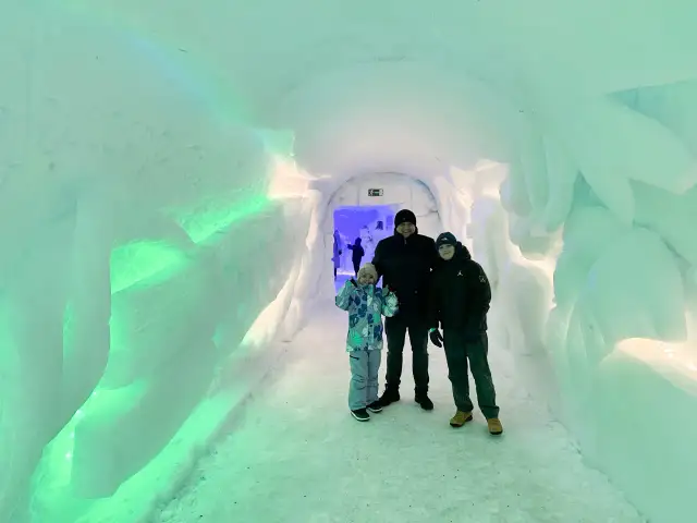 Rodzina w lodowym tunelu, gdzieś w okolicy wioski świętego mikołaja. Napis "Welcome to the..." wyryty w lodzie.
