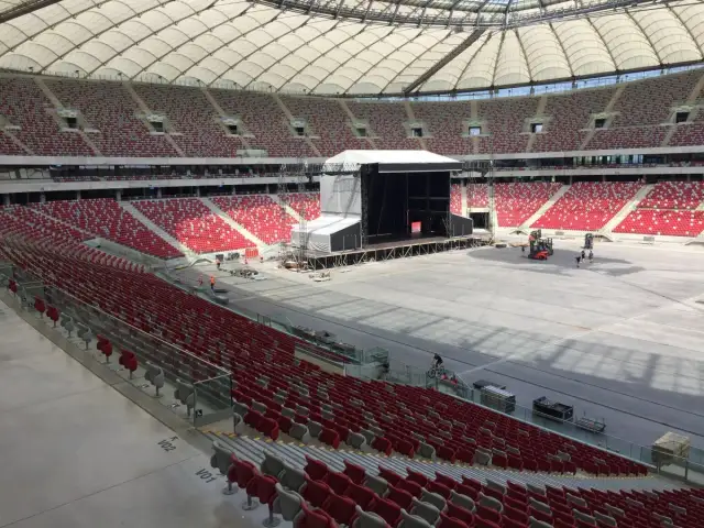 Przygotowania do koncertu Depeche Mode w Warszawie. Ogromny stadion z pustymi czerwonymi trybunami i sceną w budowie.