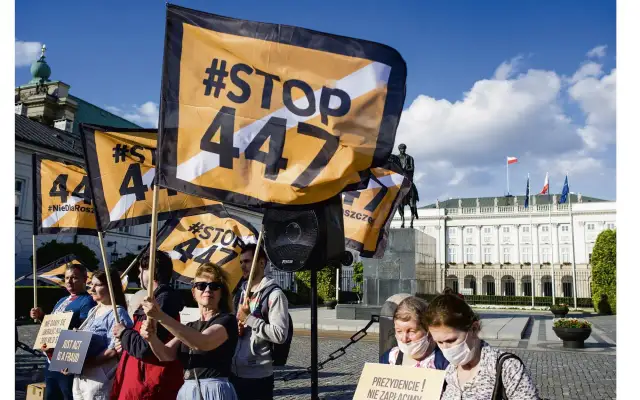 Protestujący trzymają flagi z napisem #STOP 447. Tło stanowi Pałac Prezydencki w Warszawie.