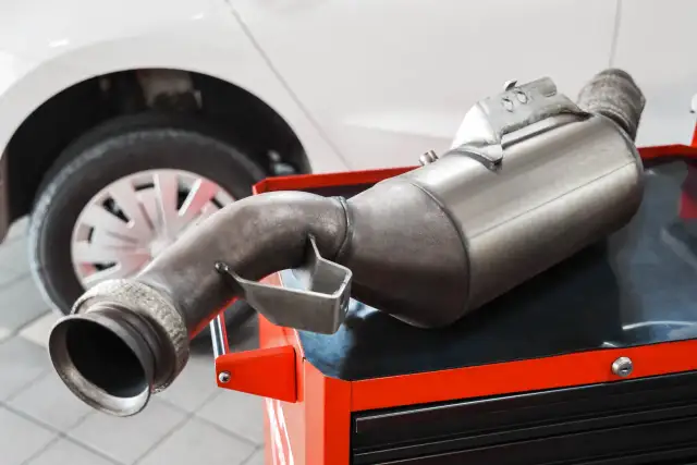 Filtr DPF na czerwonej skrzynce narzędziowej, obok koła samochodu. Zastanawiasz się, ile popiołu w dpf?
