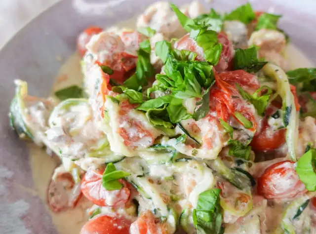 Cremiges low carb lachs Gericht mit Zucchini-Nudeln, Kirschtomaten und frischem Basilikum.