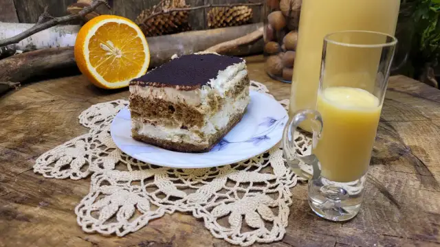 Sernik z pomarańczami i likierem pomarańczowym, obok połówka pomarańczy i kieliszek z likierem.
