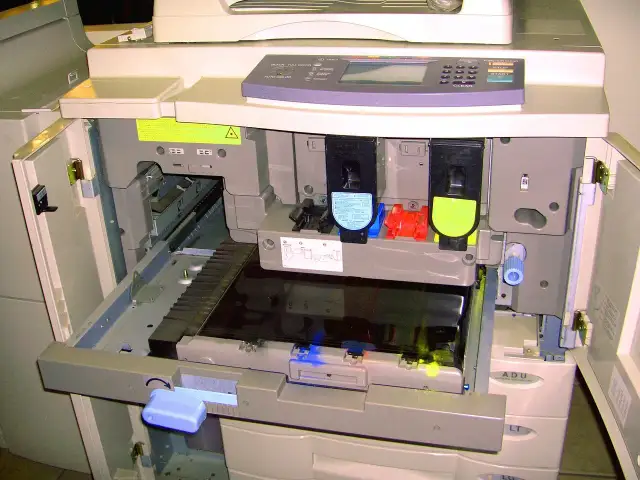 Wnętrze drukarki z widocznymi tonerami i mechanizmem.