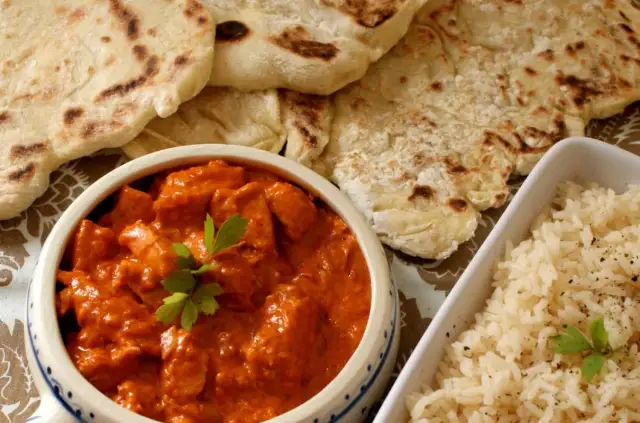 Pyszny butter chicken z chlebkiem naan i ryżem. Idealny posiłek dla miłośników indyjskich smaków.