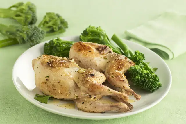 Dos codornices al ajillo doradas y jugosas, servidas con brócoli tierno y perejil fresco. Un plato delicioso y lleno de sabor.