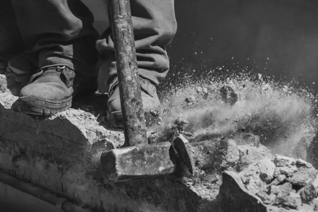 Młot rozbija beton, tworząc chmurę pyłu. To może być kara za wyburzenie ściany nośnej.