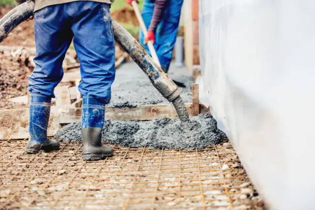 Pracownicy wylewają beton na zbrojenie. Warto wiedzieć, ile waży litr betonu, by oszacować obciążenie konstrukcji.