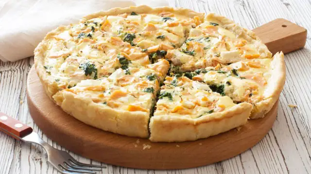 Tarta de espinacas y salmón, recién horneada y cortada en porciones, lista para disfrutar.
