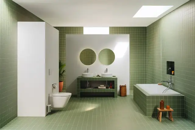Moderno baño con azulejos verdes, doble lavabo, bañera y WC. Un espacio ideal para renovar el baño con estilo y funcionalidad.