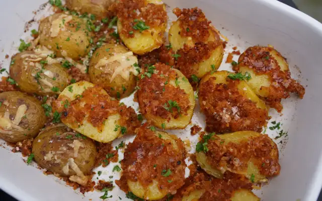 Knusprige parmesan kartoffeln mit Petersilie und grobem Salz bestreut, bereit zum Genießen.