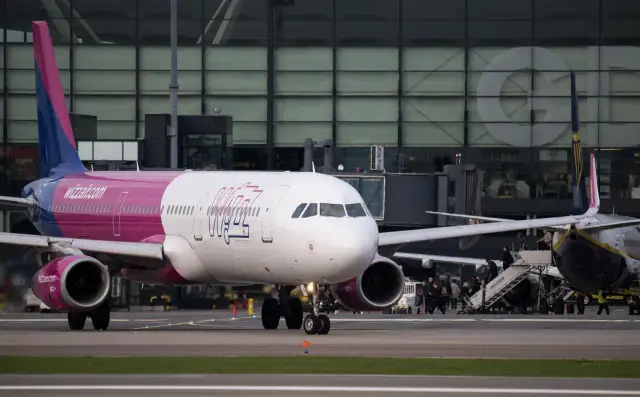 Samolot Wizz Air na płycie lotniska przed budynkiem terminala.
